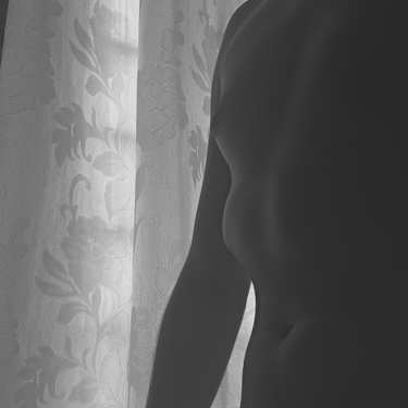 Silueta artística en blanco y negro de un torso frente a una cortina.