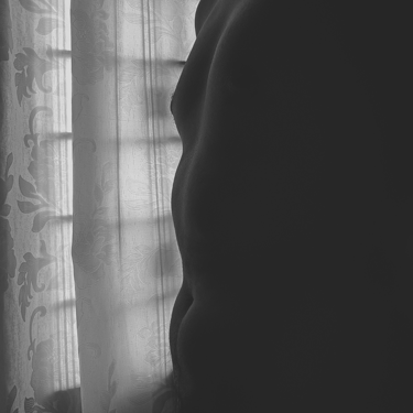 Imagen de hombre de abdomen y cortina translúcida en blanco y negro.