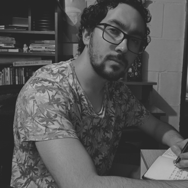 Hombre con gafas y camisa de palmeras escribiendo, retrato en B&N.