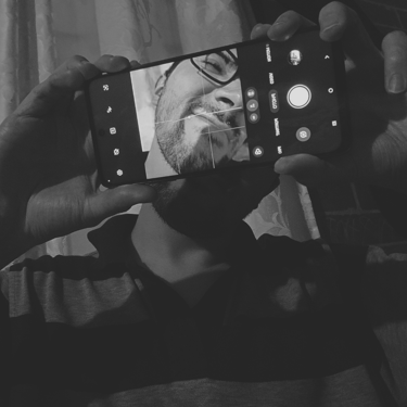 A black-and-white self-portrait taken with a cell phone reveals the face against the shadow.