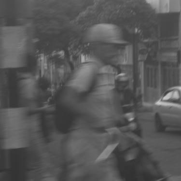 Imagen urbana desenfocada de un hombre caminando con casco en la calle.