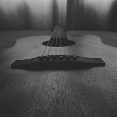 Perspectiva desde el puente de una guitarra acústica, en blanco y negro.