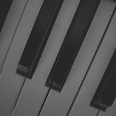 Primer plano angular de teclas de piano blancas y negras, monocromático.