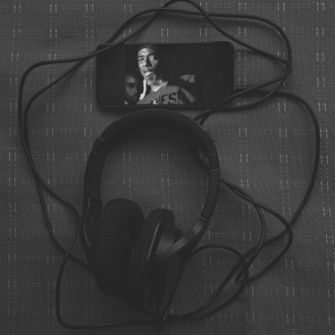 Teléfono mostrando video y audífonos de diadema en blanco y negro.