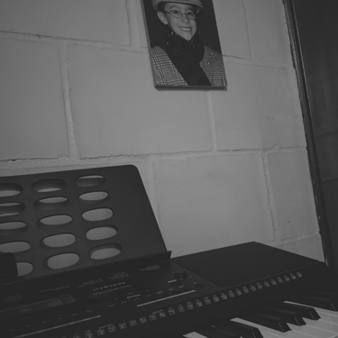 Teclado musical bajo retrato infantil en pared de bloques, bnw.