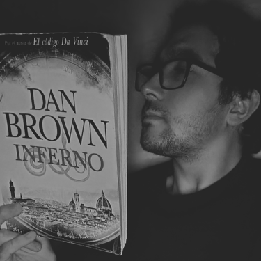 Hombre con gafas leyendo "Inferno" de Dan Brown, en blanco y negro.