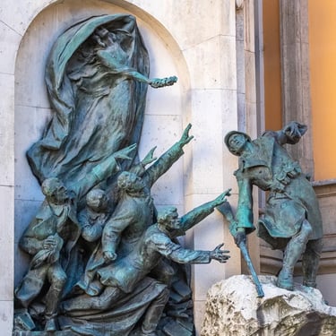 Wide-angle view of the entire heroic memorial, including the Genius figure holding a wreath above the youths.