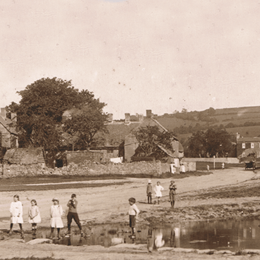 a old sepia photo of the village pond in Willersey, Gloucestershire with a road and pub beyond