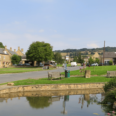 a photo of the village pond in Willersey, Gloucestershire with a road and pub beyond