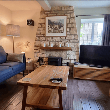 a photo of the lounge at Campion Cottage with a sofa, stone chimney and a coffee table