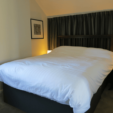a photo of a bedroom at Campion Cottage with a bed backed with grey curtains