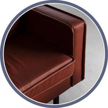 A close-up of a red-brown leather sofa, focusing on the armrest and backrest.