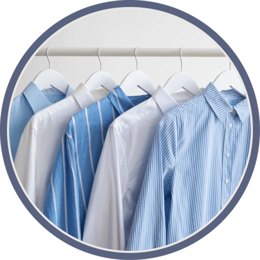 Five light blue and white dress shirts hanging on a rack.