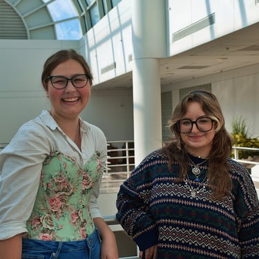 Two young college women best friends smiling and laughing in the camera.