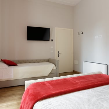 Camera Tripla Deluxe con balcone a Verona, vista del letto singolo aggiuntivo con TV a parete e arredi moderni.