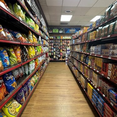 Aisle in Round Hill Market with shelves stocked with various snacks, including chips and crackers, under bright lights.