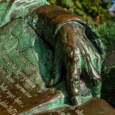 Hand of Anonymous resting on the Gesta Hungarorum, beside the ornate P initial.