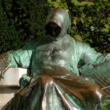 Upper body of Anonymous with both hands visible, hood drawn low in deep shadow.