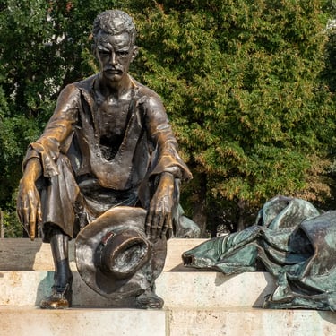 Frontal view of seated Attila József statue by the Danube, lost in thought.