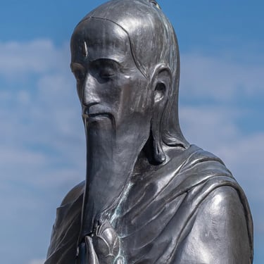 Serene head of the statue under blue sky, suggesting wisdom and calm.