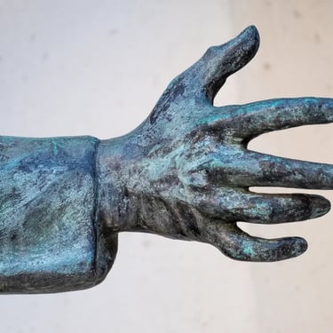 Student’s outstretched bronze hand from the memorial, reaching toward the front.