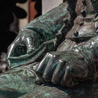Both hands of the seated Kölcsey statue resting on his lap.