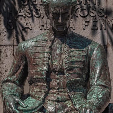 Upper body of Kölcsey with hands resting on a book and lap.