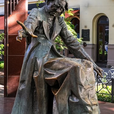 Full side view of Franz Liszt statue by László Marton in contemplative pose.