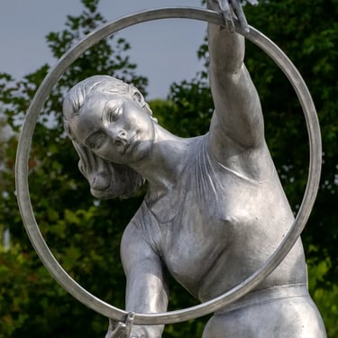 Upper body of third gymnast girl, gazing through hoop with focused, playful expression.