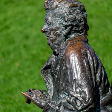 Upper body and side profile of seated Hilda Gobbi statue, showing poised posture.