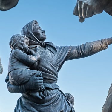 Woman sheltering her child among figures surrounding the Lajos Kossuth memorial.