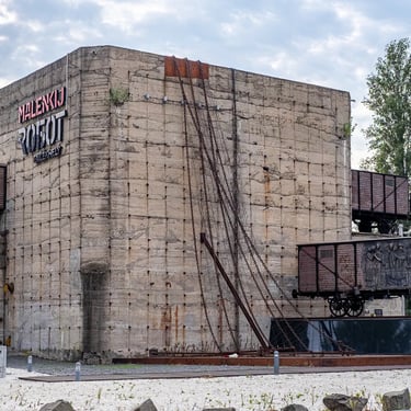 Wide view of memorial with blocks, chains, wagons, and sculpted groups evoking exile.