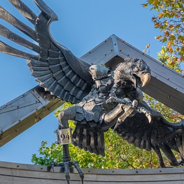 Bronze eagle swooping down with claws and wings extended, symbolising Nazi occupation.