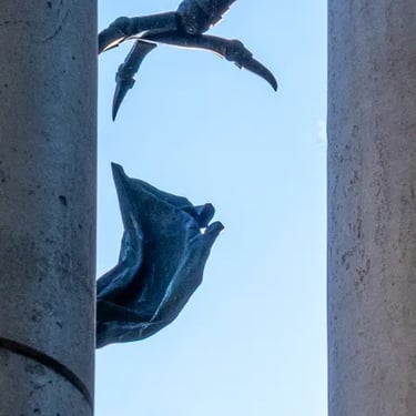 Backlit detail of eagle’s claw and angel’s wing, highlighting tense clash of forms.