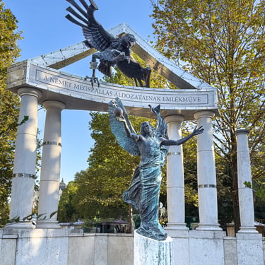 Front view of monument on Szabadság tér, angel, eagle and columns framed for debate.