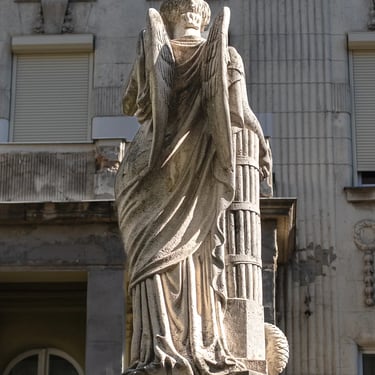 Rear view of the Peace statue atop the fountain, with building facade behind.