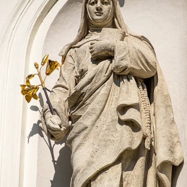 Statue of Saint Margaret holding flowers, gazing outward on the church’s left facade.