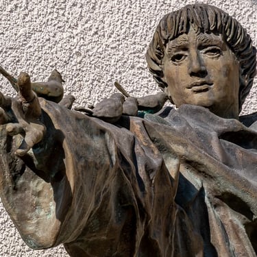 Upper body of Saint Francis, hand extended with birds, expressing gentle reverence.