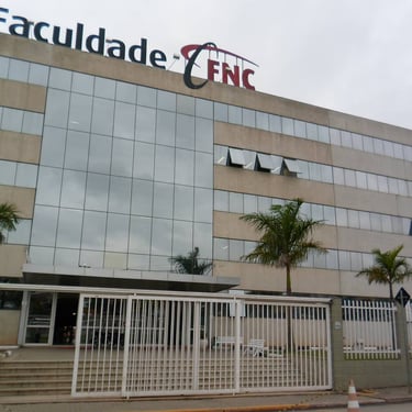 Fachada do prédio da "Faculdade FNC", um edifício moderno com múltiplos andares, parede de vidro espelhado e portão de grades