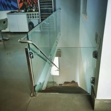 Vista superior de uma escada com guarda-corpo de vidro e corrimão de aço inox, com um portão de vidro para segurança instalad