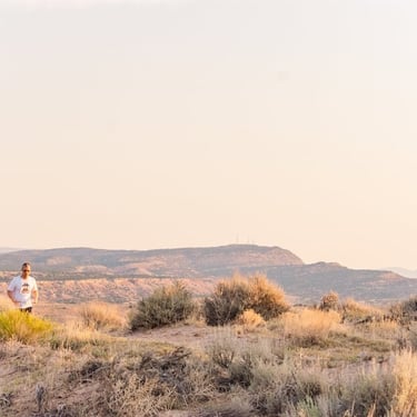 A man trail running through a high desert landscape with sagebrush and distant mountains at sunrise.