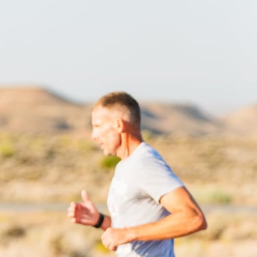 A focused man trail running outdoors on a scenic desert trail during sunrise.