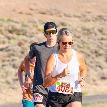 A woman and young man compete in a cross country trail running race on a desert path.