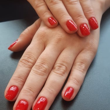 Detalhe de esmaltação vermelha em unhas quadradas, evidenciando a limpeza perfeita das cutículas e a qualidade dos materiais.