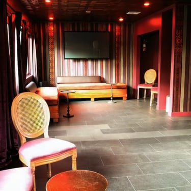 Couch with pillows in a room with striped wallpaper and decorative chairs.