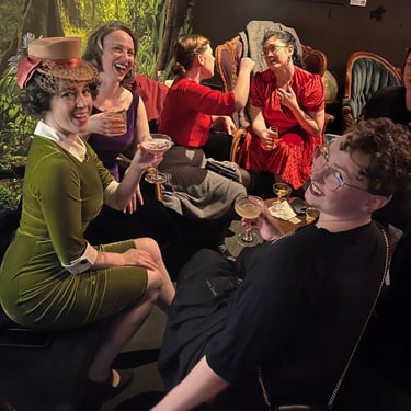 A group of people in 1920s-inspired attire socializing with drinks and dess