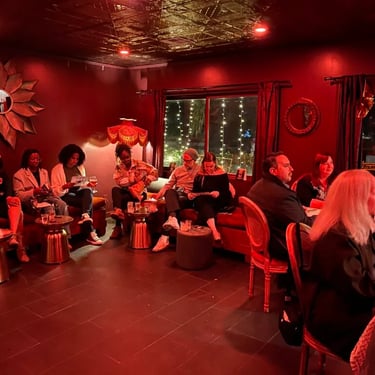People seated in chairs facing a wall in a room with dark red walls.