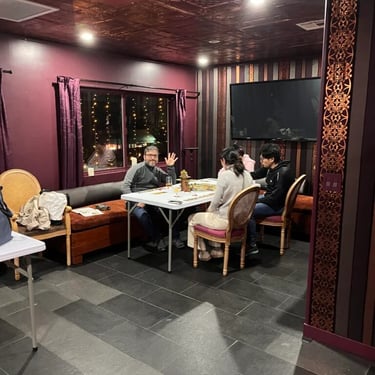 Group of people seated at a table in a room with dark red walls.