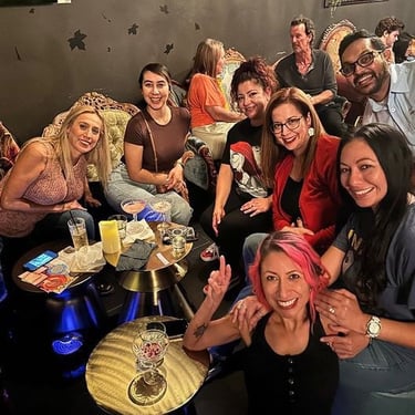 Group of friends smiling and seated around drinks in a cozy lounge setting.