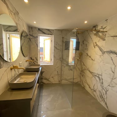 a bathroom with a marbled wall and a glass shower